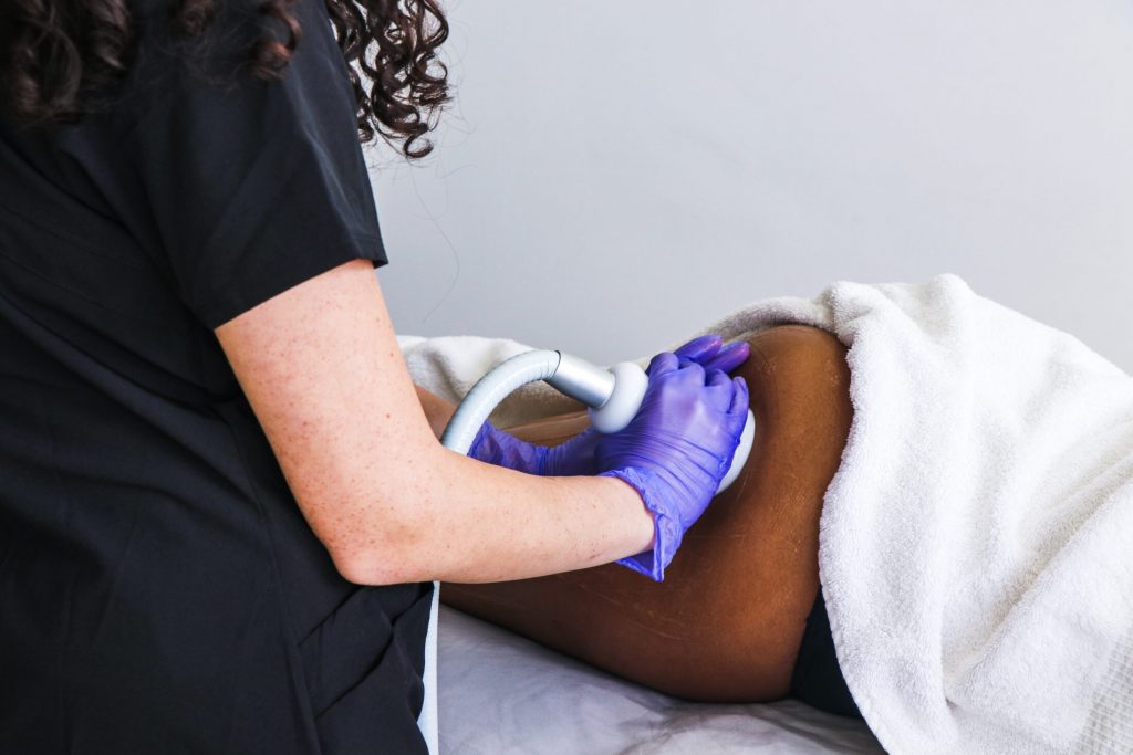 A person undergoing CryoSkin treatment, with a handheld device on their skin, aimed at toning and tightening.